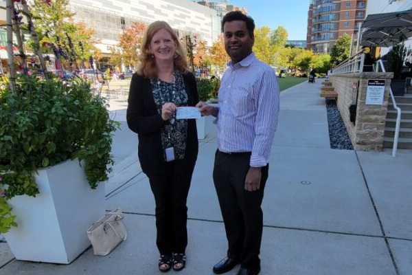 Two people holding a ceremonial check outdoors