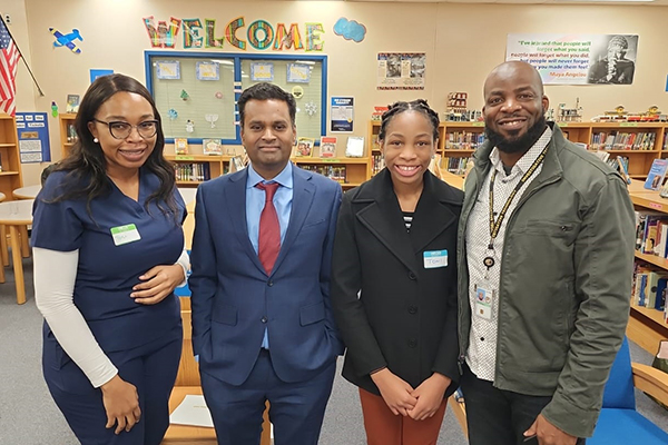 Four people standing together in a classroom